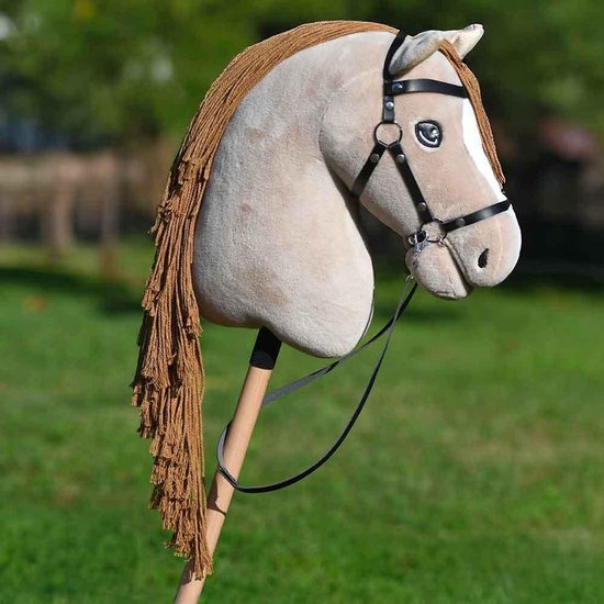 Stokpaard in crème met bruine manen, zwart hoofdstel, op een houten stok tegen een groene achtergrond.