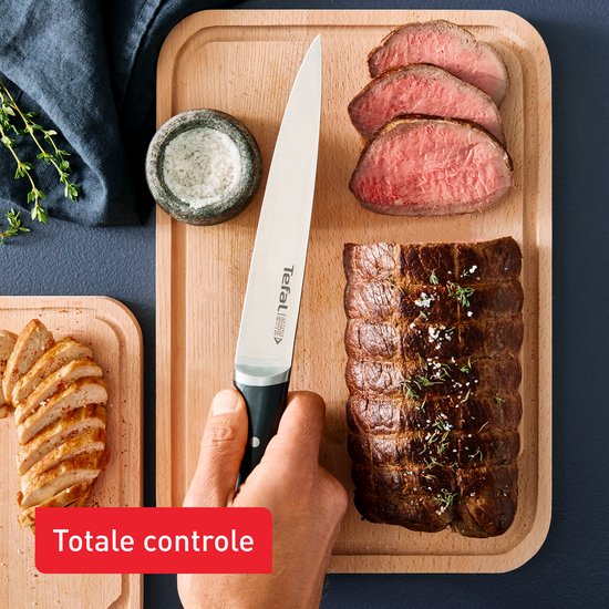 Hand snijdt rosbief en kipfilet met Tefal koksmes op snijplank