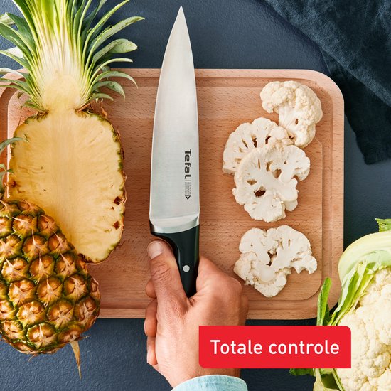 Hand snijdt ananas en bloemkool met Tefal koksmes op snijplank
