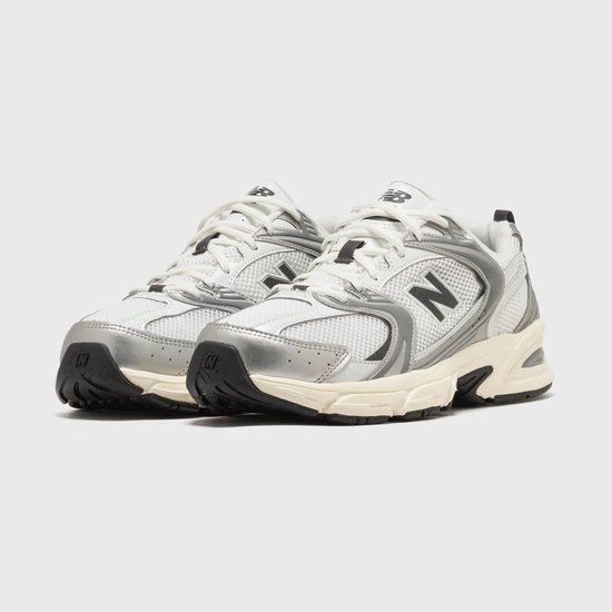 Paar witte New Balance 530 sneakers, zilveren details, zwarte 'N' en crèmekleurige zolen.
