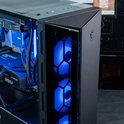Zijpaneel van een zwarte gaming pc met getextureerd metaal en een glasplaat met blauw verlichte ventilatoren.
