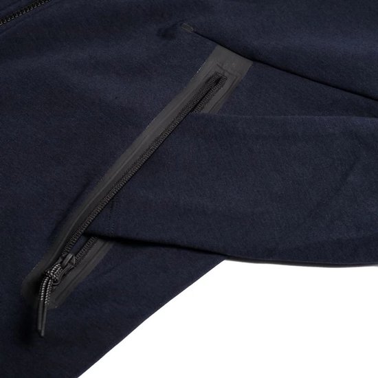 Detail van een donkerblauw Nike Tech vest met een waterdichte rits.