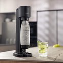 Zwarte Sodastream Gaia bruiswatertoestel met bruiswater, naast een glas met drank.