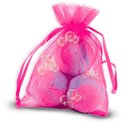 Drie roze en paarse badbruisballen in een doorzichtig roze netzakje met bubbels.