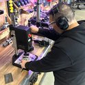 Man in gehoorbescherming die een boormachine bedient in een werkplaats.