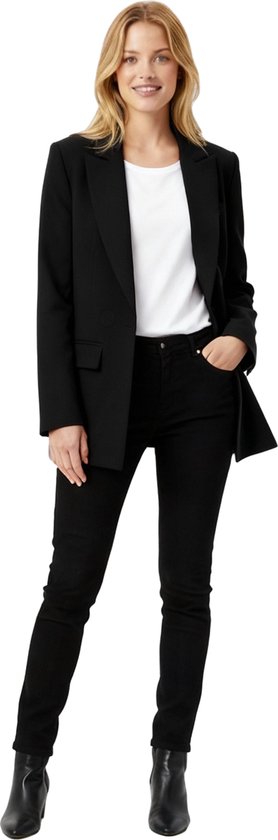 Model draagt een zwarte oversized blazer met open revers, een witte top, zwarte broek en zwarte laarsjes.