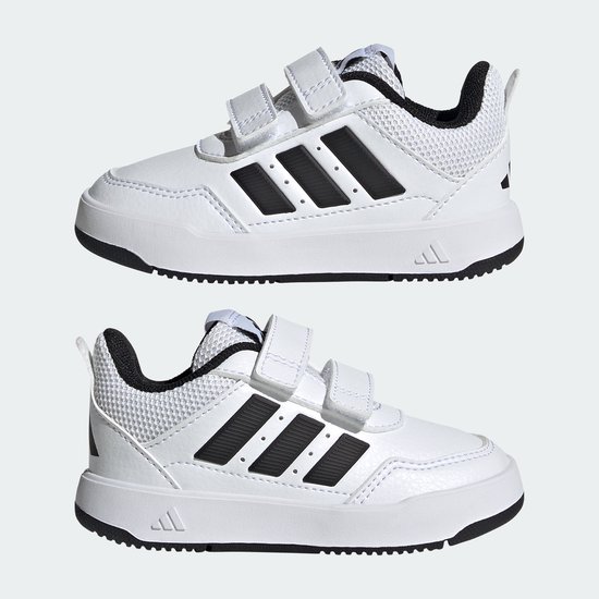 Twee witte peuterschoenen met zwarte strepen op de zijkant en klittenbandsluiting.