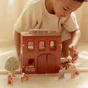 Kind speelt met houten brandweerkazerne, brandweerman-poppetjes en een brandweerwagen.
