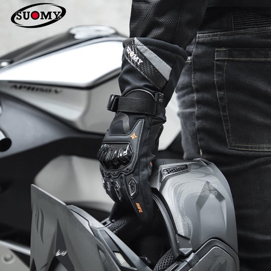 Persoon in zwarte kleding draagt een zwarte motorhandschoen met rode details, naast een motorfiets en helm.