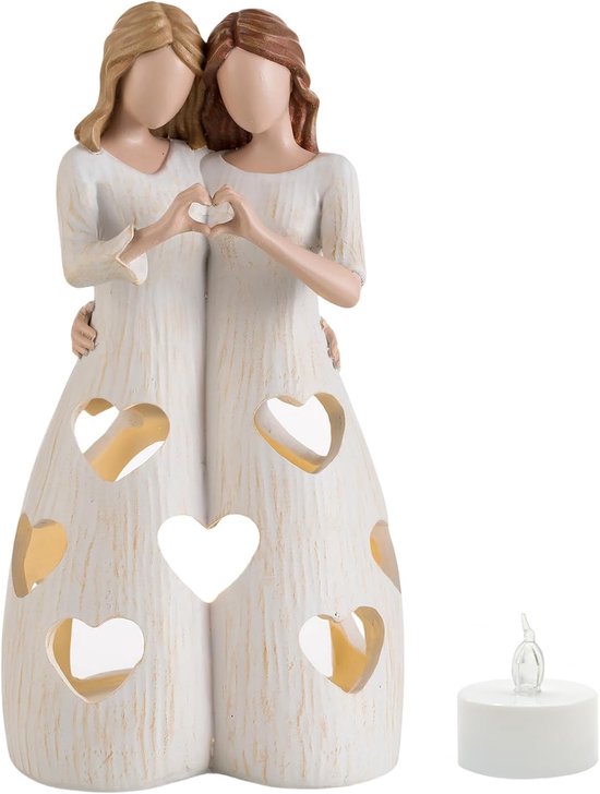 Close-up van een harsbeeld van twee vrouwen in witte jurken, met hartvormige uitsparingen en hun handen in een hartvormige pose. Een LED-kaars staat ernaast.