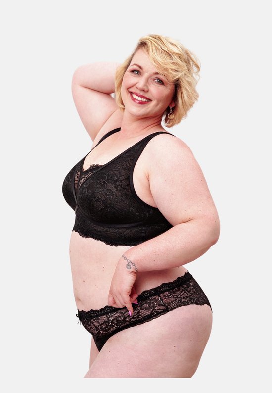 Model met blonde krullen draagt een zwarte kanten bralette en slip.
