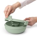 Mains plaçant le couvercle sur une boîte à salade vert pâle avec diviseur et pot à vinaigrette.