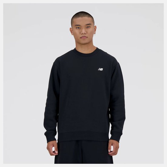 Man in zwart New Balance sweatshirt met wit logo op de borst. De trui is van voren te zien.