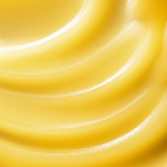 Close-up van de gele, romige textuur van Garnier sorbetcrème in golvende lijnen.