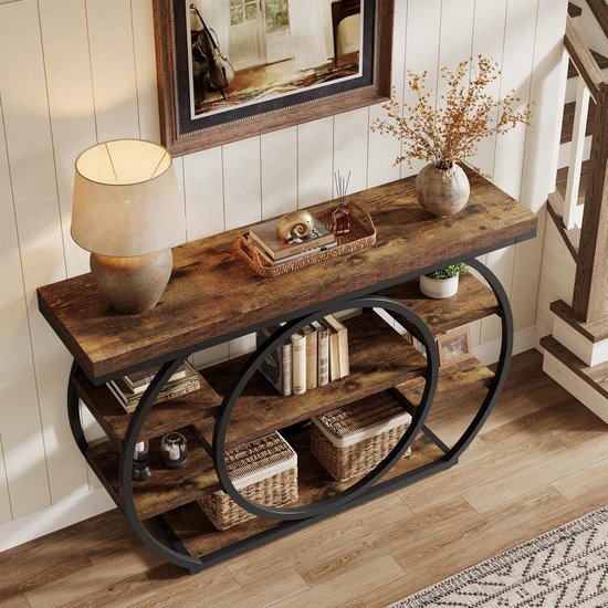 Bruine consoletafel met zwarte metalen cirkel-structuur, 5 open vakken en decoraties zoals boeken en manden, vanuit een hogere hoek gefotografeerd.