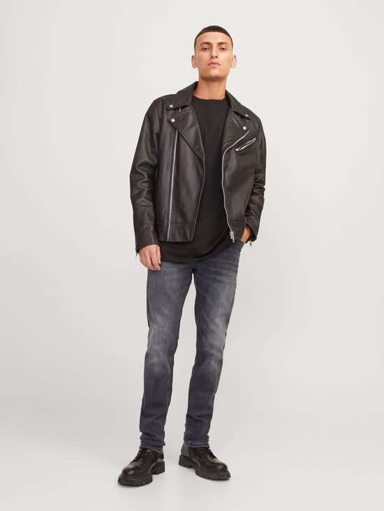 Man met zwart T-shirt, zwarte leren bikerjack en grijze jeans.