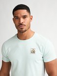 Close-up van een lichtgroen T-shirt met een opgedrukte postzegel met bloemen.