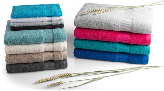 Pile de serviettes de différentes couleurs comme le bleu, le turquoise, le fuchsia, le gris et le blanc, avec des tiges de blé.
