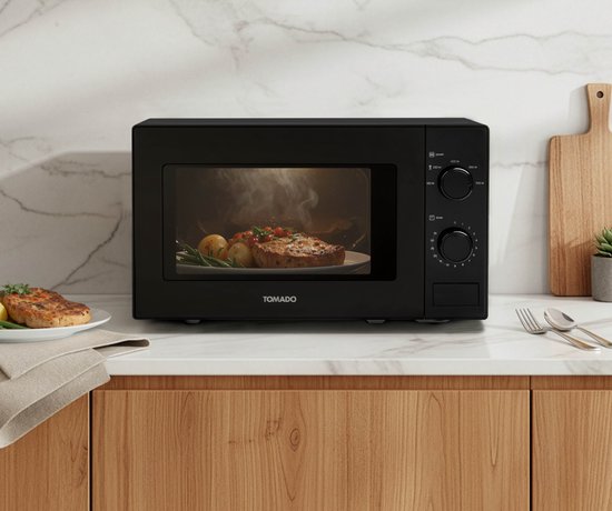 Zwarte Tomado magnetron met een kookplaat met een stuk vlees en aardappelen binnenin.