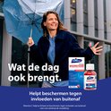 Vrouw met paraplu onder de regen. Naast haar een Davitamon Compleet Weerstand verpakking en pot met pillen. Tekst: 'Wat de dag ook brengt. Helpt beschermen tegen invloeden van buitenaf.'