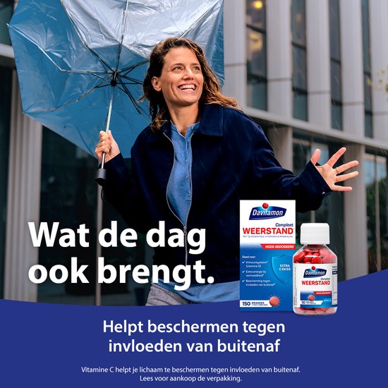 Vrouw met paraplu onder de regen. Naast haar een Davitamon Compleet Weerstand verpakking en pot met pillen. Tekst: 'Wat de dag ook brengt. Helpt beschermen tegen invloeden van buitenaf.'