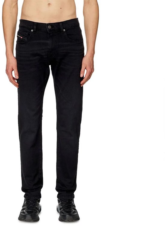 Man in zwarte jeans, van voren gezien. De broek heeft zakken aan de voorkant.