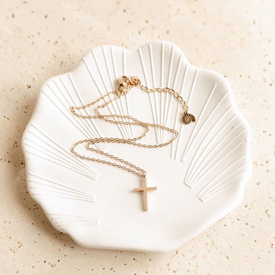 Roségouden ketting met kruishanger op een schelpvormig schaaltje.