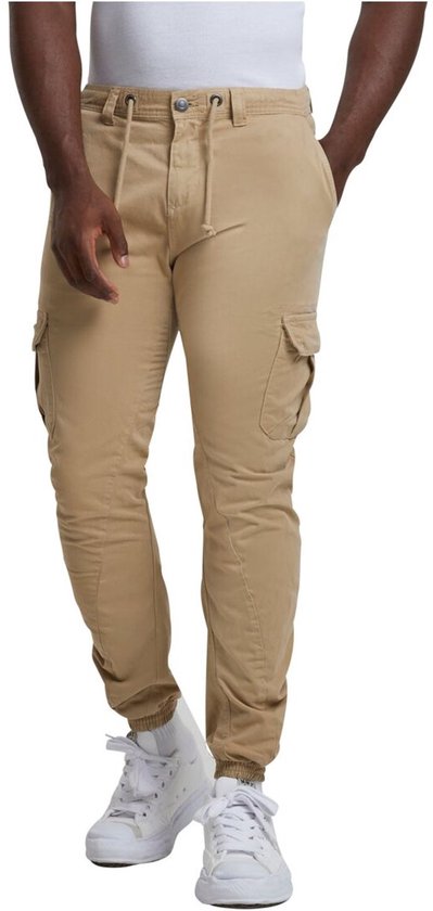 Man in beige cargo broek met trekkoord, voorkant zichtbaar, met zakken en elastische enkelbanden.