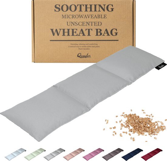 Grijze Qomfor pittenzak met een stapel graan, naast een kartonnen doos met de tekst 'SOOTHING MICROWAVEABLE UNSCENTED WHEAT BAG'.