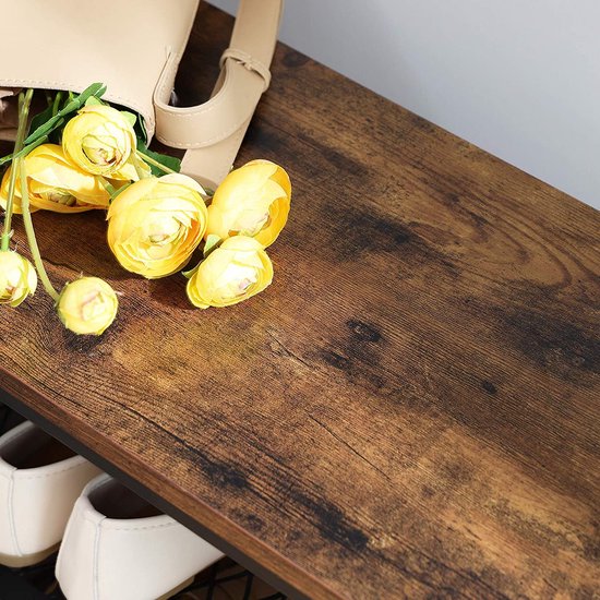Detail van een bruin houten plank met gele bloemen en een beige tas.