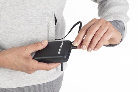 Close-up van handen die een zwarte powerbank aansluiten op een grijze hoodie.