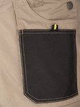 Salopette beige avec une poche noire et une boucle jaune et noire, avec un bouton STØRVIK.