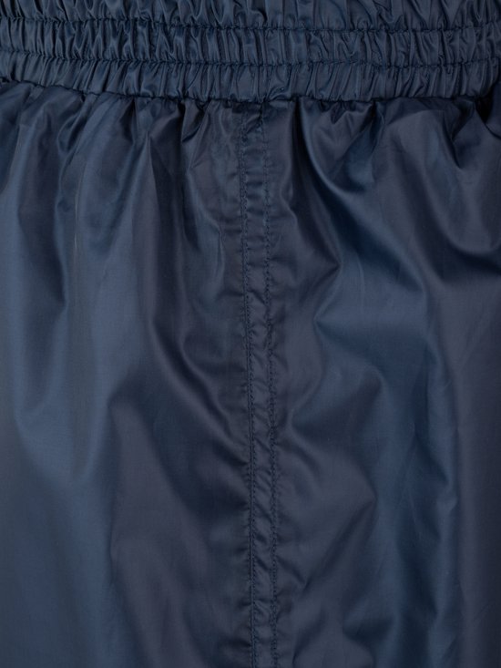 Detail van de elastische tailleband en de naden van een donkerblauwe regenbroek.