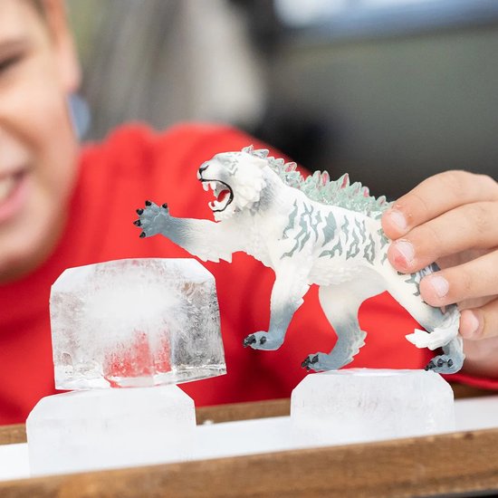 Kind houdt witte tijgerfiguur met grijze strepen en ijskristallen vast, bij ijsblokken.