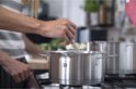 Persoon in de keuken die in een roestvrijstalen kookpot roert met een garde.