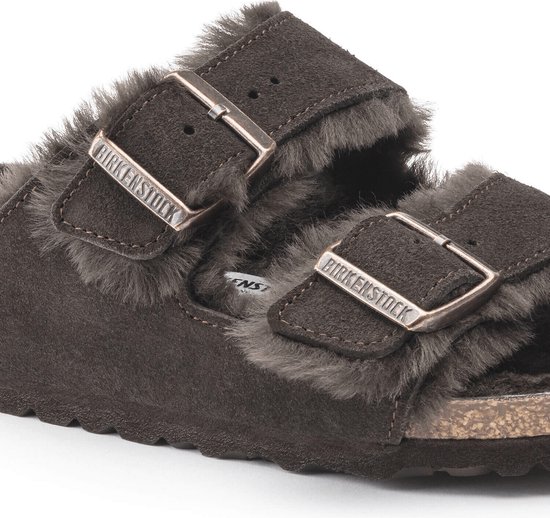 Detailopname van de gespen en lammenvacht voering van donkerbruine Birkenstock Arizona pantoffels.