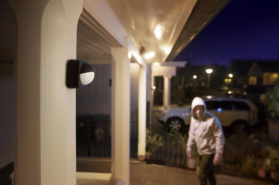 Zwarte bewegingssensor aan huis gemonteerd, tijdens een nachtelijke scene.