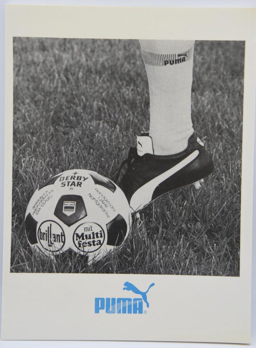 Voetbal met PUMA-sokken en schoenen op gras.