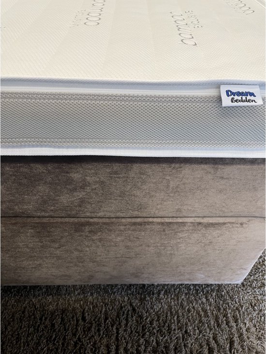 Sluit de matras af met de blauwe 'Dream Bedden' label, op een taupe bedbodem.