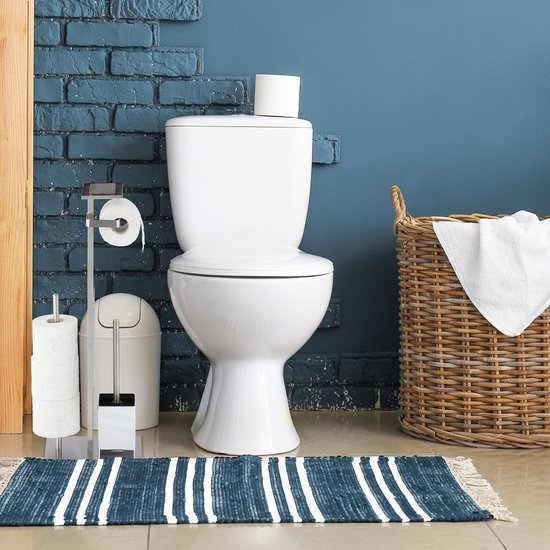 Zilverkleurige toiletrolhouder met wc-borstel, naast een toilet met blauwe bakstenen muur.