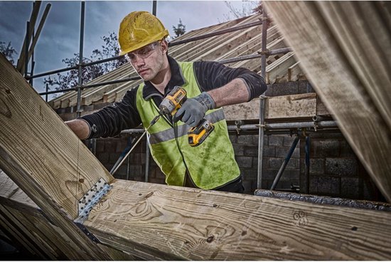 Man met geel-zwarte DeWalt slagschroevendraaier aan het werk op een bouwplaats met houten balken.