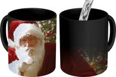 Magische Mok - Foto op Warmte Mokken - Koffiemok - De kerstman met op de achtergrond een kleurrijke kerstboom - Magic Mok - Beker - 350 ML - Theemok