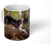 Mok - Een zwart-witte border collie die over een boomstam springt - 350 ML - Beker