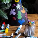 Zwarte lampenkap met kleurrijke, abstracte vormen. Meerdere stiften liggen verspreid.