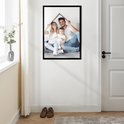 Une famille de trois personnes (parents et enfant) en t-shirts blancs et jeans, assis par terre et formant une maison avec leurs mains.