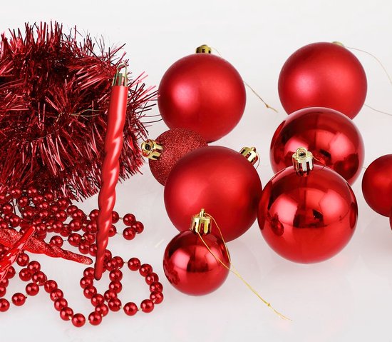 Collectie rode kerstdecoraties: kerstballen, een spiralige kaars, perlenkettingen en glitterdraad.