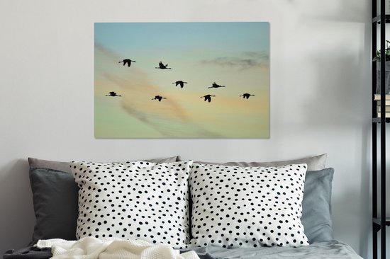 Tableau sur toile Un ciel bleu-jaune avec huit grues - 90x60 cm - Décoration murale