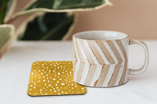 Sous-verre doré à motif de Noël blanc à côté d'une tasse sur une table claire.
