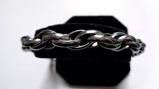 Bracelet large en acier inoxydable avec des maillons entrelacés, présenté sur un support noir.