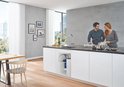 Een stel in een moderne keuken met een chroom GROHE kraan, met onderbouw filter en een koppel-kookplaat.